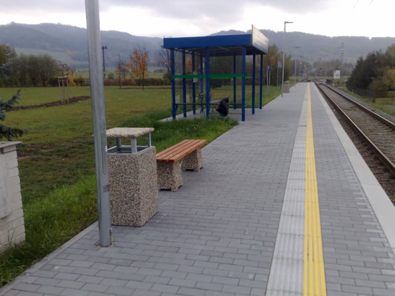Betonový odpadkový koš HUGO se stříškou a popelníkem ve vymývaném povrchu oblázek na vlakové stanici